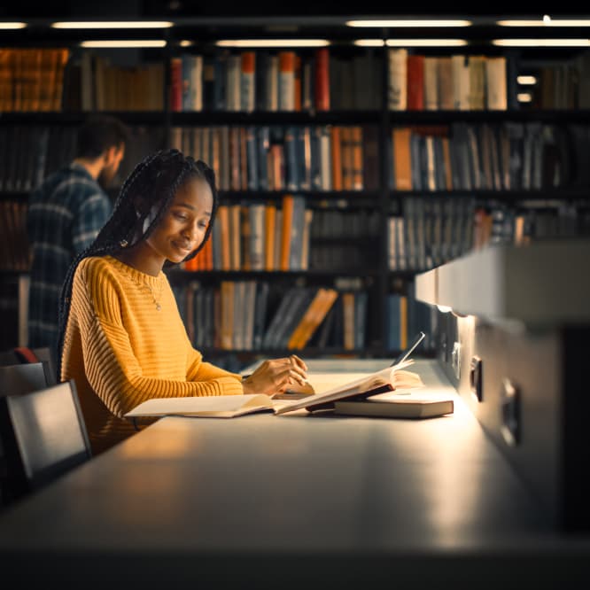 Woman studying at night in a library. 