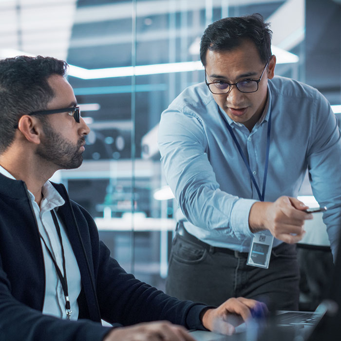 Two men working together pointing at screen.