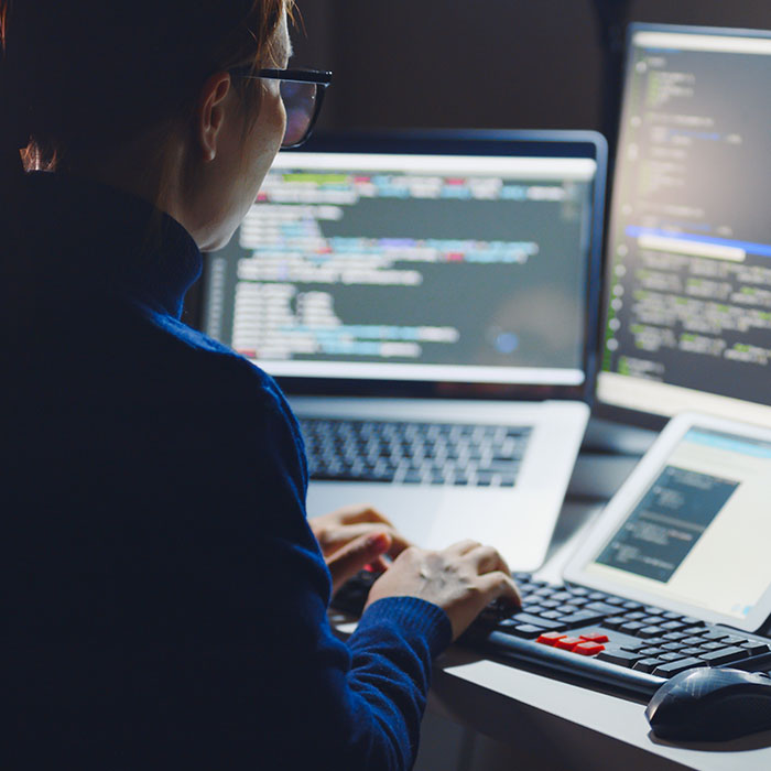 Woman working at desk with 3 monitors