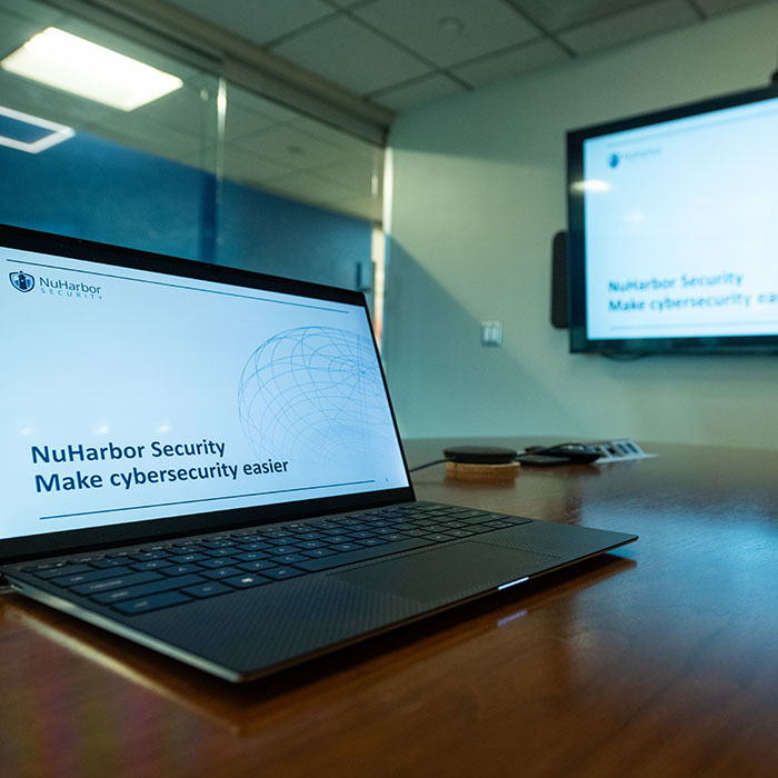 Computer on a table with text saying NuHarbor Security Make cybersecurity easier